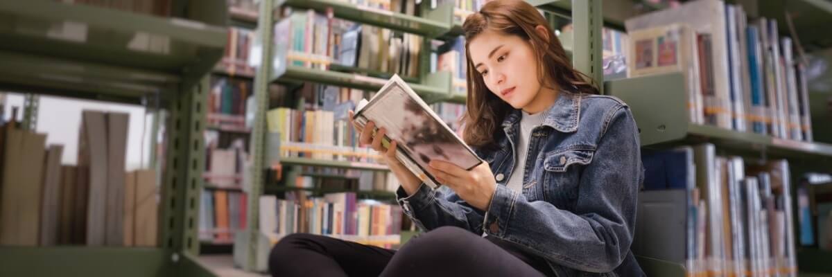 mulher-lendo-livro-em-biblioteca